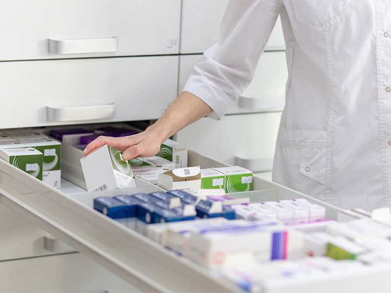 Apothekerin holt gewünschtes Medikament aus Schublade – Medikamente kaufen mit individueller Beratung direkt in der Apotheke.