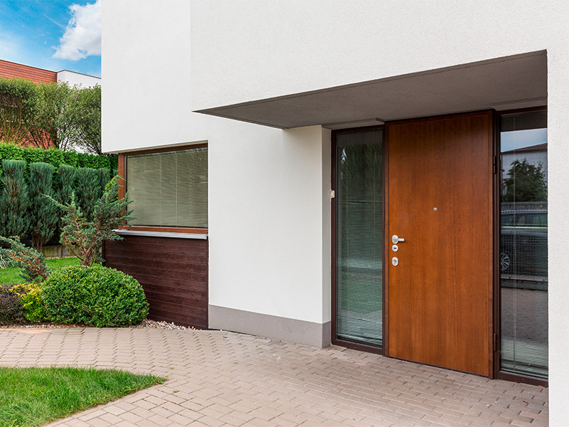 Moderner Hauseingang mit massiver Holztür, klaren Linien und minimalistischer Erscheinung.