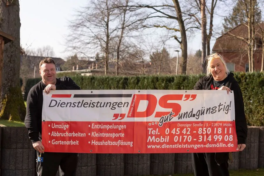 Großes Banner der Dienstleistungen DS mit Kontaktdaten sowie Inhaber Dennis Steckner und Ehefrau im Außenbereich