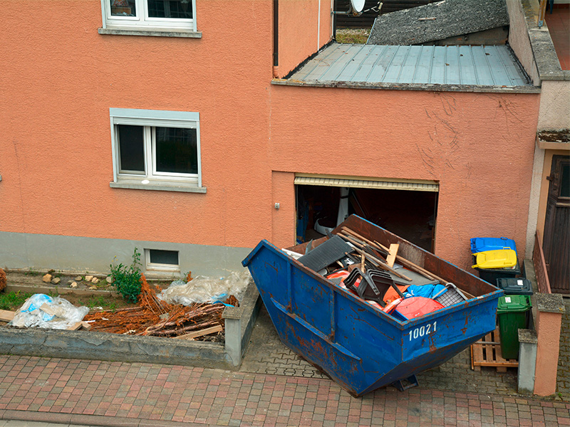 Außenaufnahme eines Wohnhauses mit blauem Container während einer Entrümpelung in Geesthacht bei Wohnungsauflösung laufenden Arbeiten vor Ort