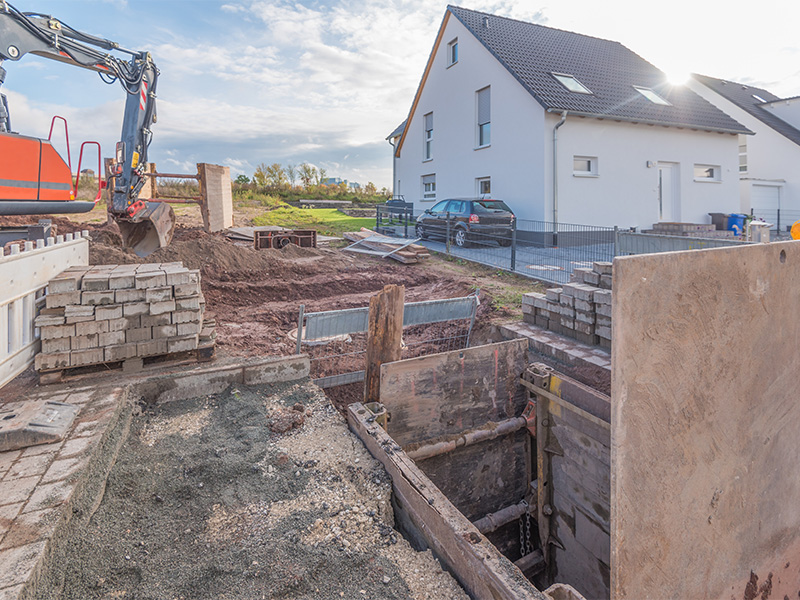 Arbeiter führen präzise Kanalanschlussarbeiten im Tiefbau in Ratzeburg aus, moderne Maschinen sichern effiziente Bauausführung.