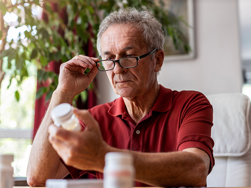 Älterer Mann zu Hause nimmt Medikamente, Apotheker überprüft sicher Wechselwirkungen in Ratzeburg für optimale Gesundheit.